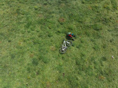 Çiçekli çayır dağında dağ bisikleti süren kadının hava manzarası.