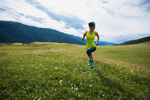 stock image Fitness woman  runner running at flowering grassland mountain top