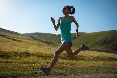 Fitness kadın koşucusu çiçek açan çayırların tepesinde koşuyor.