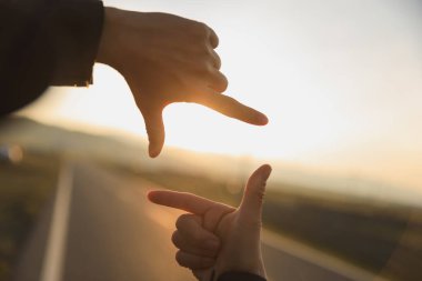 Gün doğumuna karşı resim çerçevesi şeklinde eller