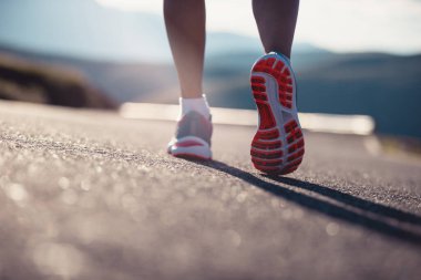 Gün batımında dağ yolunda koşan fitness kadın koşucusu
