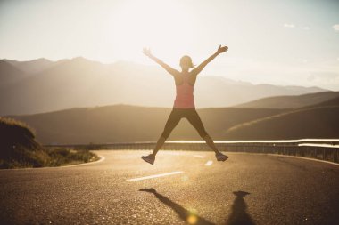 Fitness kadın koşucusu gün batımında atlıyor