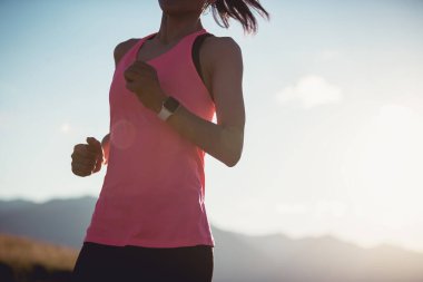 Fitness woman runner running at sunset mountain top clipart