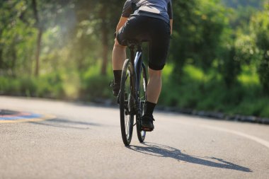 Yaz parkında bisiklet süren bir kadın.