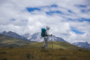 Sırt çantalı bir kadın yüksek rakım dağlarında yürüyüş yapıyor.
