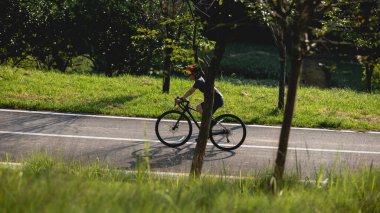 Yaz parkında bisiklet süren kadın bisikletçi.