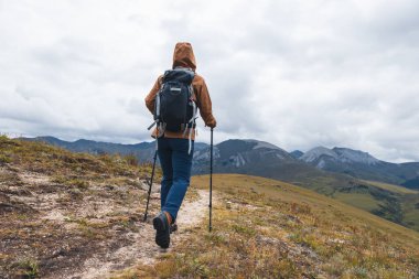 Sırt çantalı bir kadın yüksek irtifada dağ yürüyüşü yapıyor.