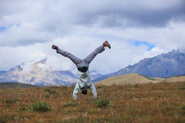 Yüksek rakımlı dağ çayırında bir handstand yapıyor kadın yürüyüşçü