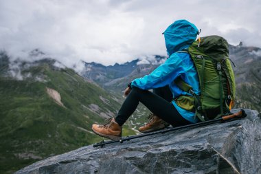 Yürüyüş yapan kadın yüksek rakımlı dağın tepesindeki manzaranın tadını çıkarıyor.
