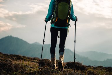 Günbatımında yürüyüş yapan bir kadın yüksek irtifa dağının tepesinde