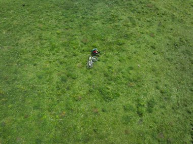 Dağ bisikleti süren bir kadının hava manzarası. Çiçekli çayırların tepesinde.