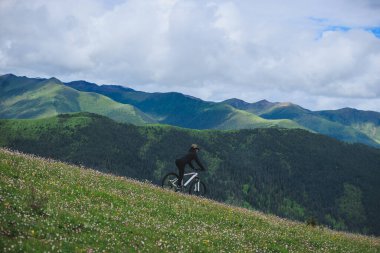 Güzel dağ tepesinde dağ bisikleti süren Asyalı kadın.