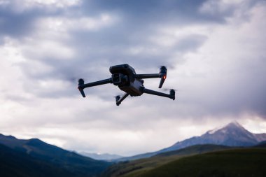 İHA yüksek irtifada, dağın tepesinde uçuyor.