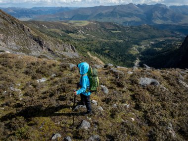 Yükseklik dağlarında yürüyüş yapan başarılı bir sırt çantası taşıyan kadın. 