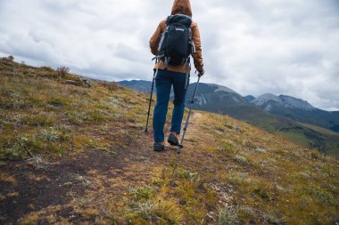 Sırt çantalı bir kadın yüksek irtifada dağ yürüyüşü yapıyor.