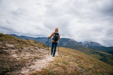 Sırt çantalı bir kadın yüksek irtifada dağ yürüyüşü yapıyor.