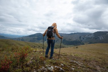 Sırt çantalı bir kadın yüksek irtifada dağ yürüyüşü yapıyor.