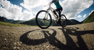 Dağın tepesinde bisiklet süren bir kadın.