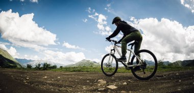 Dağın tepesinde bisiklet süren bir kadın.