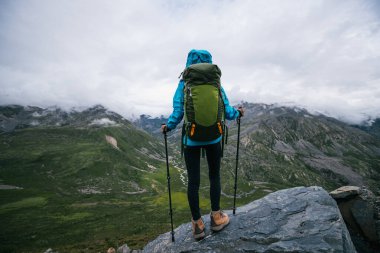 Sırt çantalı bir kadın yüksek irtifa dağına tırmanıyor.