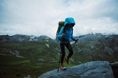 Sırt çantalı bir kadın yüksek irtifa dağına tırmanıyor.