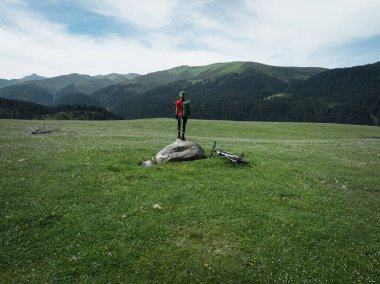 Çiçekli çayır dağında dağ bisikletiyle uçan kadın bisikletçi manzarası