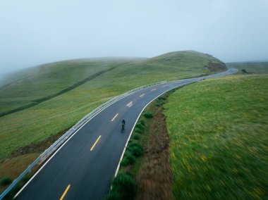 Motion blurred cyclist riding bike on grassland mountain top trail clipart