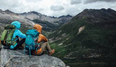Yürüyüş yapan iki arkadaş yüksek rakımlı dağın tepesindeki manzaranın tadını çıkarırlar.