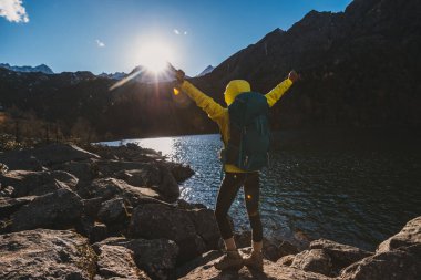 Sırt çantalı bir kadın, sonbahar yüksek irtifada kollarını açar.
