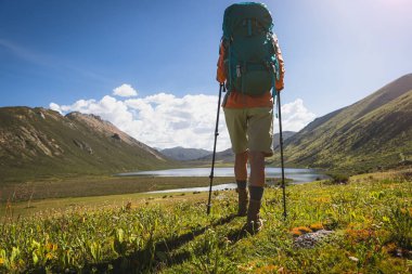 Sırt çantalı kadın yürüyüşçü deri botlar giyiyor yüksek rakımlı çayır dağlarında yürüyüş yapıyor.