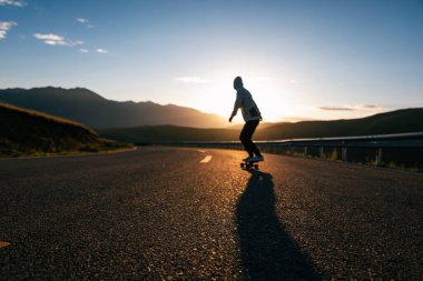 Kaykaycı, Sunset Dağı tepesindeki yolda kaykay yapıyor.