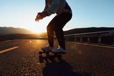 Kaykaycı, Sunset Dağı tepesindeki yolda kaykay yapıyor.