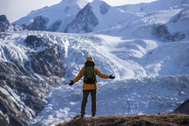 Sırt çantalı kadın yüksek irtifada asılı büyük buzulun kollarını açıyor.