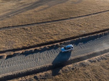 Tibet, Çin 'in ücra bir köşesindeki eğimli yolda giden off-road aracının havadan görüntüsü.