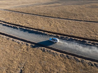 Tibet, Çin 'in ücra bir köşesindeki eğimli yolda giden off-road aracının havadan görüntüsü.