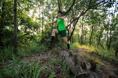 Woman trail runner running at tropical forest mountain peak