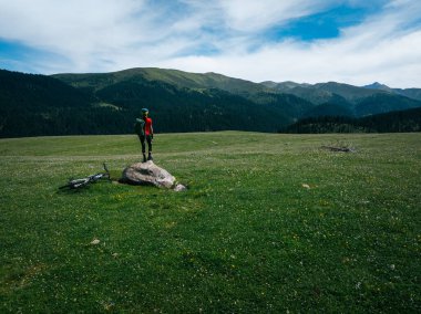 Çiçekli çayır dağında dağ bisikletiyle uçan kadın bisikletçi manzarası