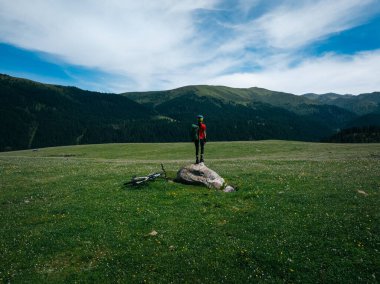 Çiçekli çayır dağında dağ bisikletiyle uçan kadın bisikletçi manzarası