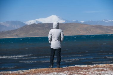 Tibet 'teki yüksek rakımlı gölde karlı dağı izleyen bir kadın.