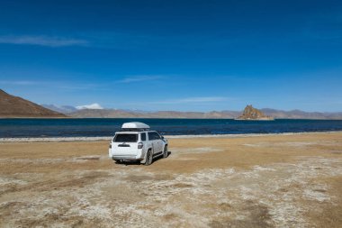 Yüksek rakımlı göl kenarında çalışan off-road aracının hava görüntüsü