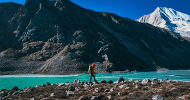 Sırt çantalı bir kadın yüksek rakım dağlarında yürüyüş yapıyor.