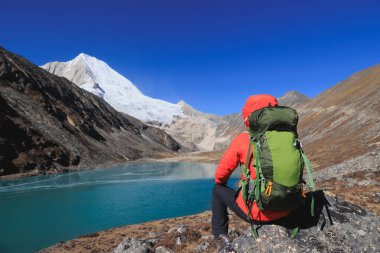 Sırt çantalı bir kadın yüksek rakım dağlarında yürüyüş yapıyor.