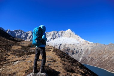 Sırt çantalı bir kadın yüksek irtifada dağ yürüyüşü yapıyor.