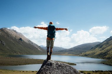 Sırt çantalı bir kadın dağın tepesinde yürüyüş yapıyor.