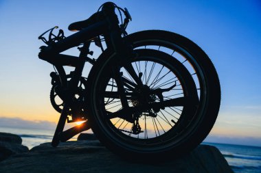 A folding bike on sunrise seaside rocka clipart