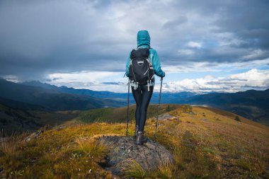 Sırt çantalı bir kadın yüksek irtifada dağ yürüyüşü yapıyor.