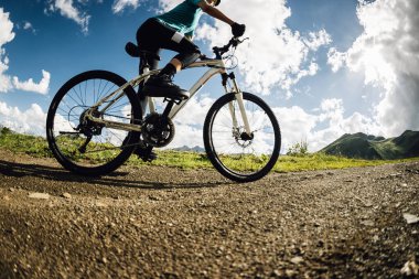 Dağın tepesinde bisiklet süren bir kadın.