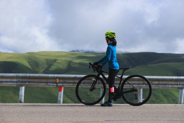 Woman cyclist with road bike enjoy the beautiful landscape clipart