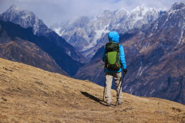 Sırt çantalı bir kadın yüksek irtifada dağ yürüyüşü yapıyor.