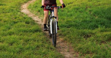 Dağ yolunda bisiklet süren kadın.